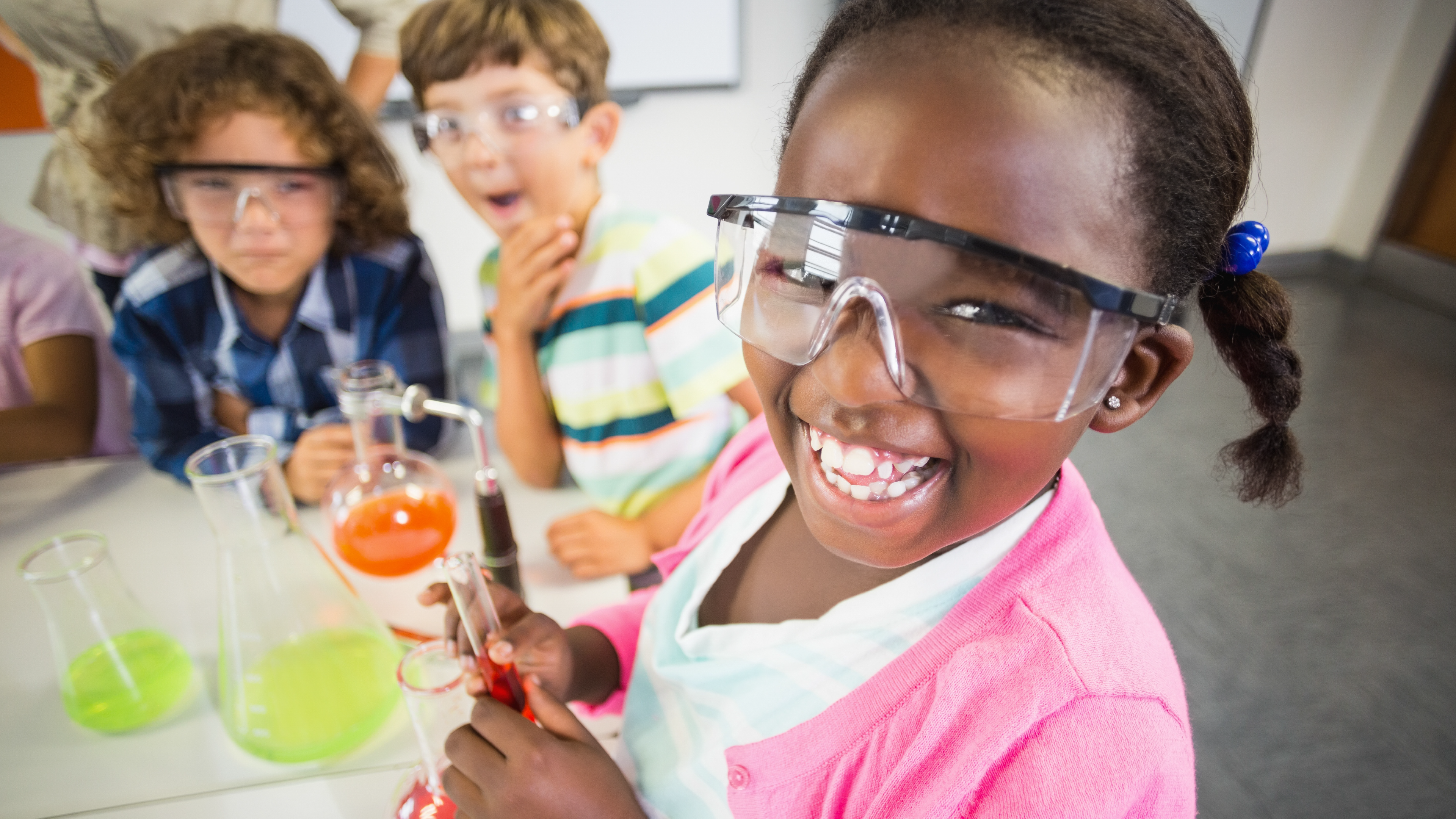 A group of fourth grade students smile during a science class experiment.